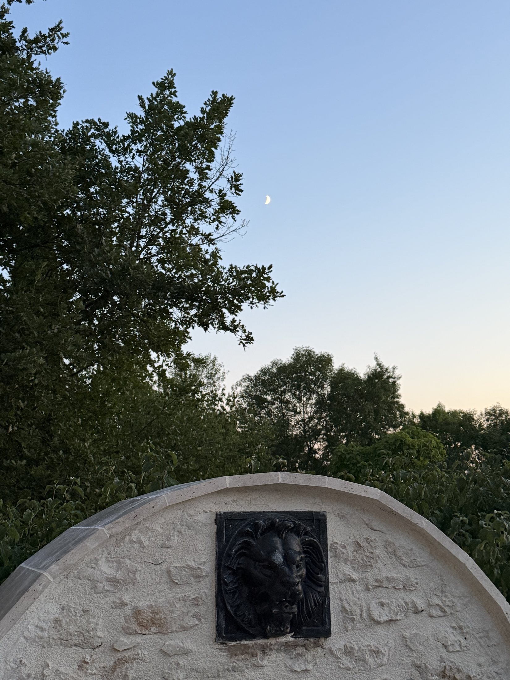 Der junge Mond über dem steinernen Löwen im Garten des Manoir Comté